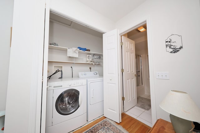 washroom featuring laundry area, washing machine and dryer, and light wood-style flooring