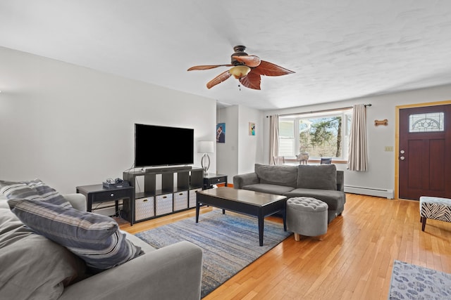 living room featuring a ceiling fan, a baseboard heating unit, and light wood-style floors