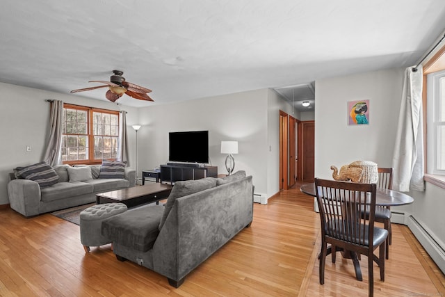 living area with light wood-type flooring, attic access, a ceiling fan, and a baseboard radiator