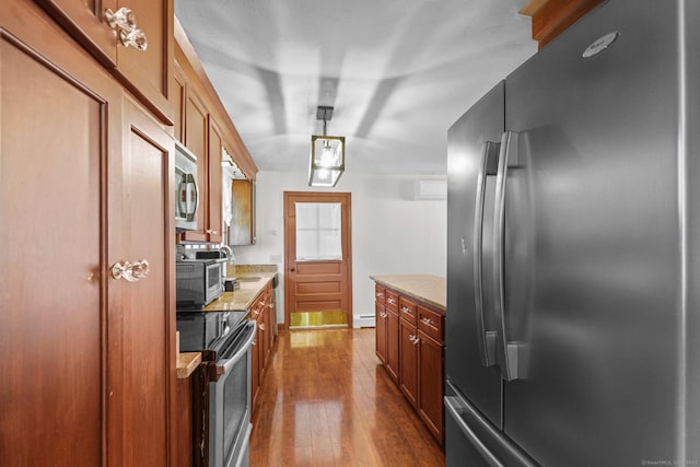 kitchen featuring a baseboard heating unit, light stone countertops, brown cabinets, stainless steel appliances, and dark wood-style flooring