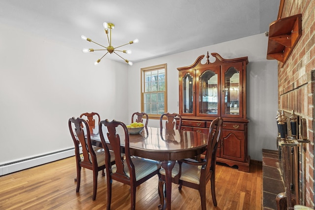 dining area featuring a baseboard heating unit, light wood finished floors, and a chandelier