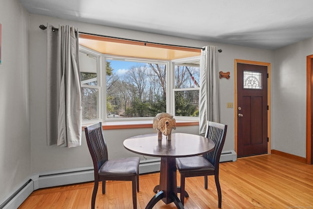 dining area featuring light wood-style flooring, a healthy amount of sunlight, and baseboard heating