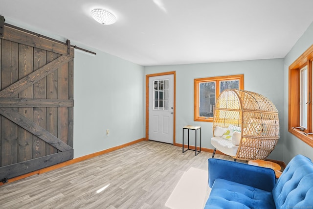 sitting room with a healthy amount of sunlight, baseboards, a barn door, and wood finished floors