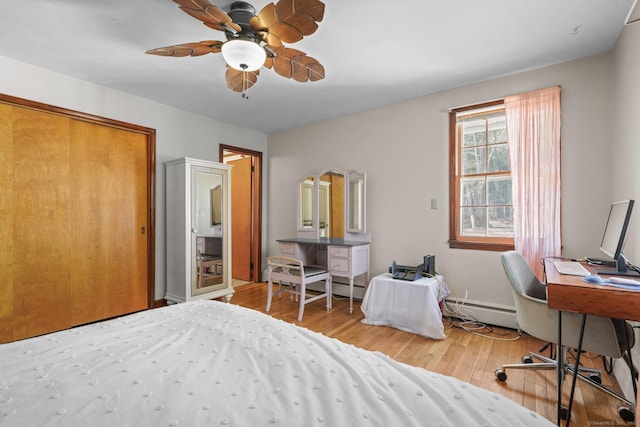 bedroom with a baseboard heating unit, wood finished floors, and ceiling fan