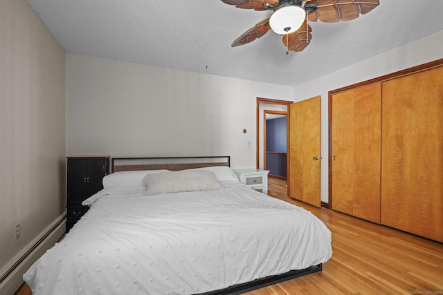 bedroom with baseboards, light wood finished floors, ceiling fan, a closet, and a baseboard heating unit