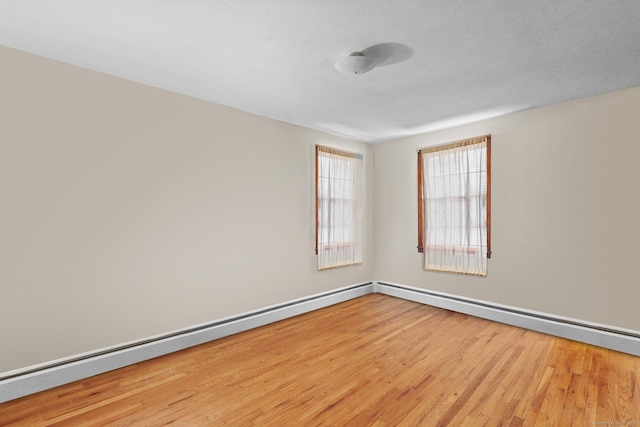 empty room featuring a baseboard heating unit and wood finished floors