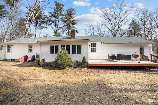 back of property featuring a wooden deck, a yard, roof with shingles, and a chimney