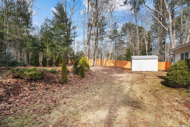 view of yard featuring a storage shed, fence, and an outbuilding