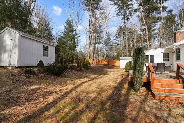 view of yard with an outbuilding, a deck, and fence