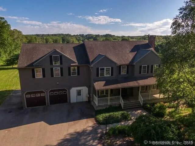 view of front of house with aphalt driveway, an attached garage, covered porch, and a chimney