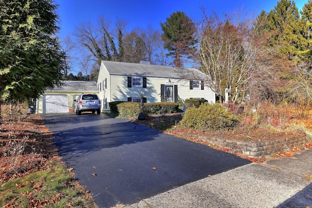 raised ranch with a garage, a chimney, and aphalt driveway