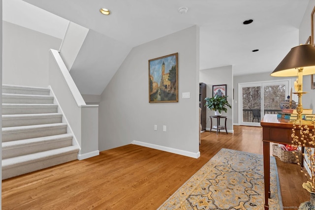 entrance foyer featuring recessed lighting, stairway, vaulted ceiling, wood finished floors, and baseboards