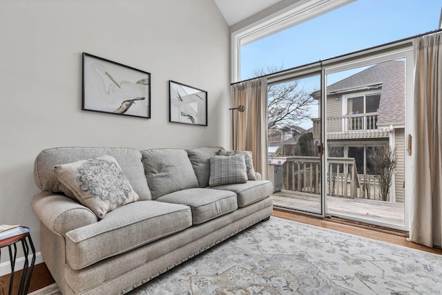 living room featuring baseboards, vaulted ceiling, and wood finished floors