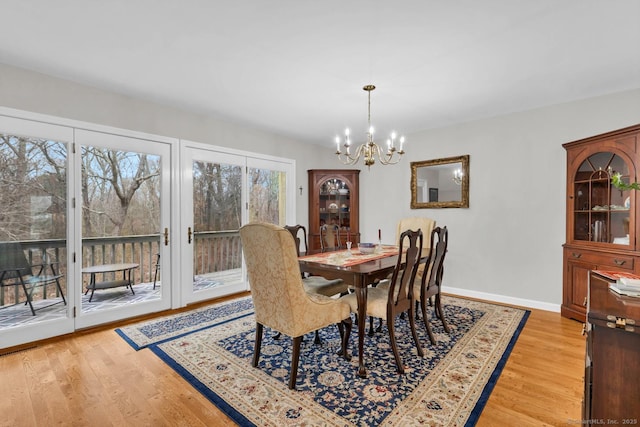 dining space with baseboards, a notable chandelier, and light wood-style floors