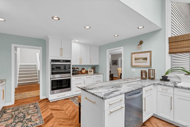 kitchen with recessed lighting, stainless steel appliances, a peninsula, white cabinets, and light stone countertops