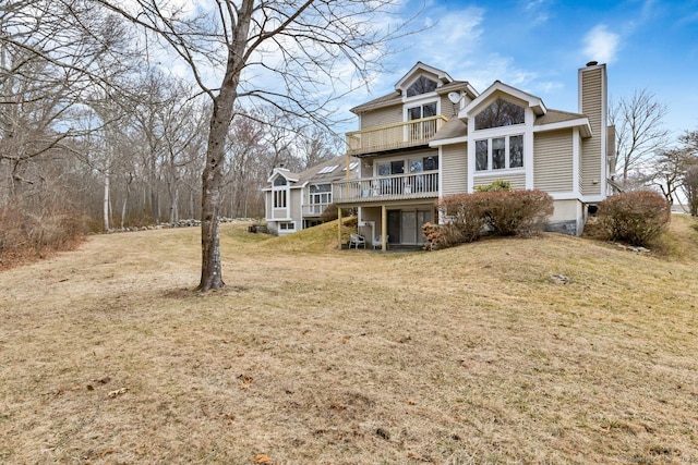 rear view of property with a yard, a chimney, and a balcony