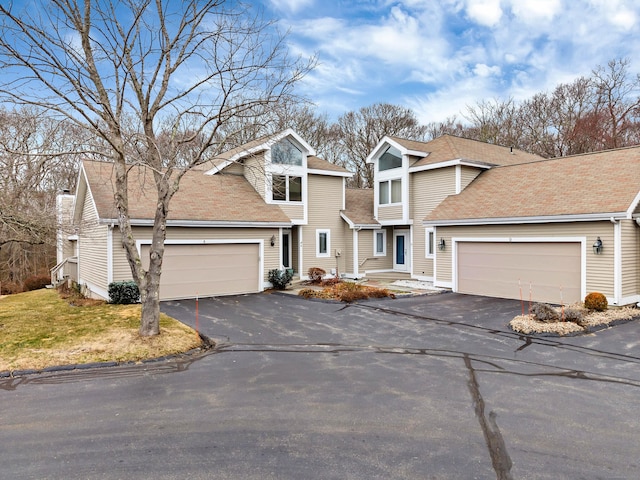 traditional-style home with a garage, roof with shingles, driveway, and a front lawn