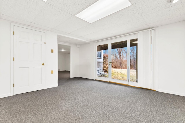 carpeted spare room with baseboards and a drop ceiling