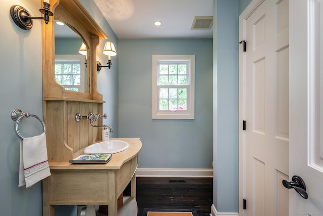 bathroom with visible vents, baseboards, plenty of natural light, and wood finished floors