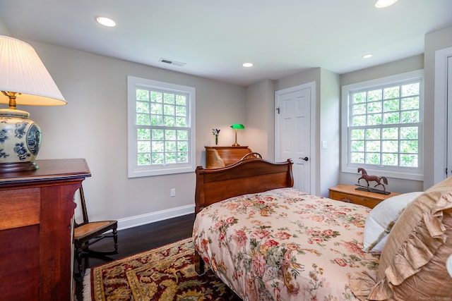 bedroom with multiple windows, baseboards, visible vents, and dark wood-style flooring