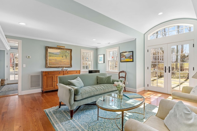 living room with crown molding, wood finished floors, visible vents, and baseboards