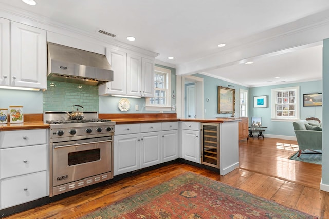 kitchen featuring visible vents, ornamental molding, beverage cooler, premium range, and wall chimney range hood