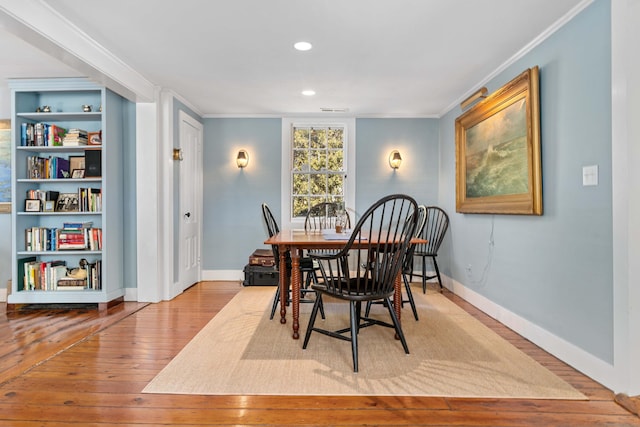 dining space featuring hardwood / wood-style floors, crown molding, and baseboards