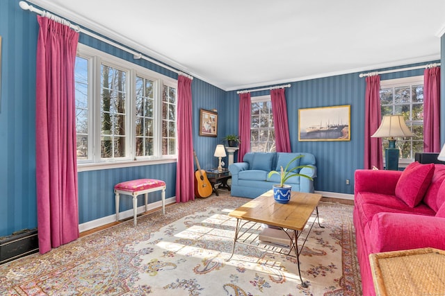 living area featuring baseboards, crown molding, and wallpapered walls