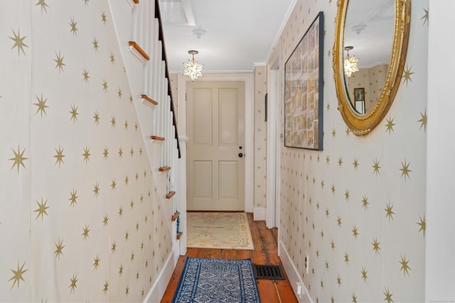 doorway with wallpapered walls, stairs, wood finished floors, and visible vents