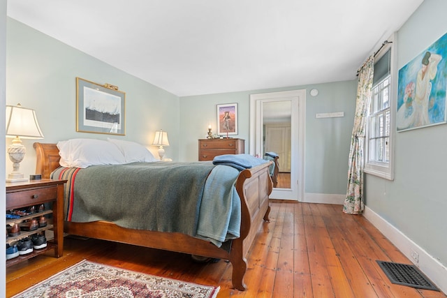 bedroom with visible vents, baseboards, and hardwood / wood-style floors