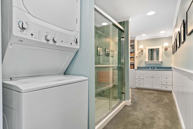 full bathroom featuring stacked washer and clothes dryer, wainscoting, a shower stall, crown molding, and vanity