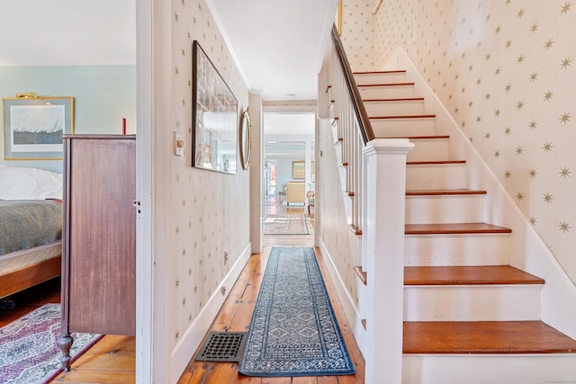 stairway featuring wallpapered walls, wood finished floors, and baseboards