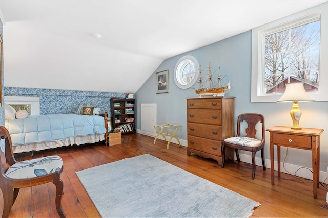 bedroom with an accent wall, vaulted ceiling, baseboards, and wood-type flooring