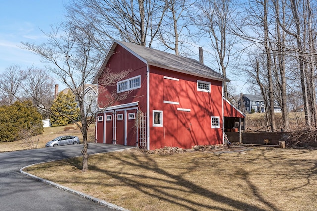 view of barn featuring a lawn, driveway, and an attached garage