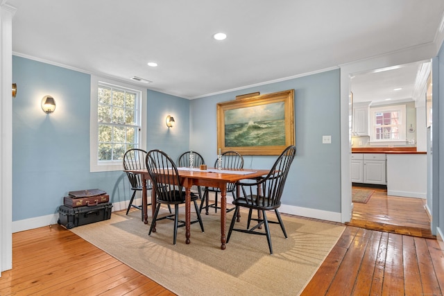 dining room with crown molding, baseboards, and light wood finished floors