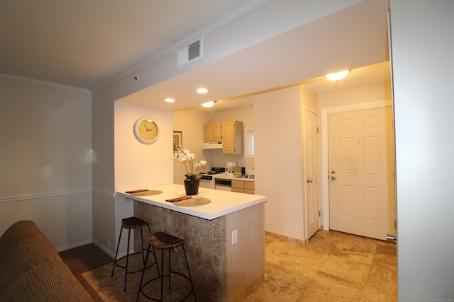 kitchen with visible vents, a kitchen breakfast bar, a peninsula, crown molding, and under cabinet range hood