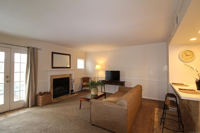 carpeted living room with ornamental molding, french doors, a tiled fireplace, and visible vents