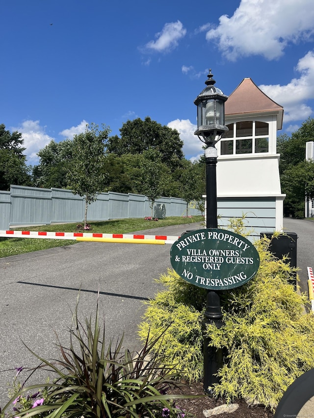 community sign featuring uncovered parking and fence