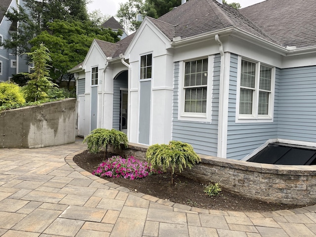 view of home's exterior featuring a patio area and a shingled roof