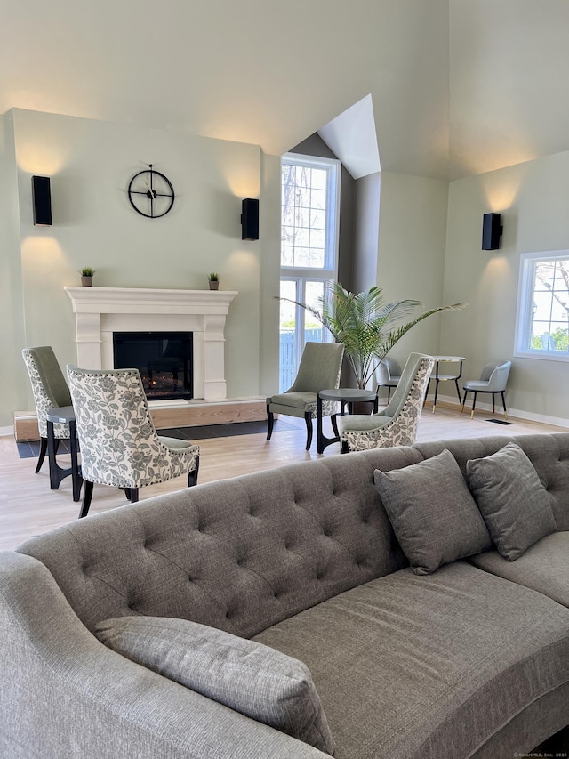 living room with lofted ceiling, baseboards, wood finished floors, and a glass covered fireplace