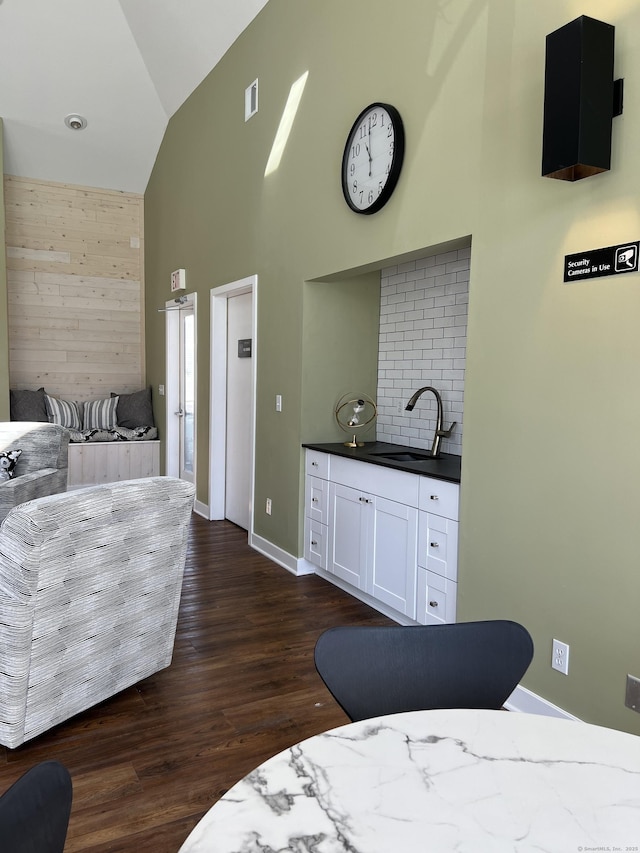 bedroom with dark wood-style flooring, visible vents, a sink, high vaulted ceiling, and baseboards