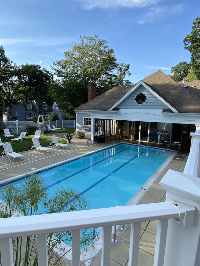 community pool with a patio area and fence