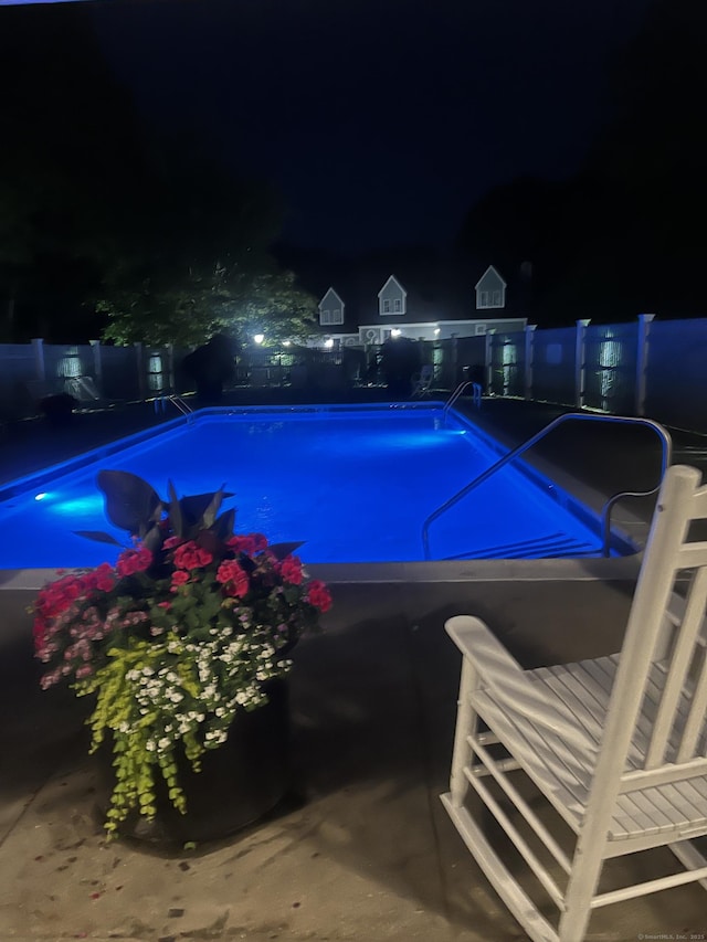 pool at twilight featuring a fenced backyard and a fenced in pool