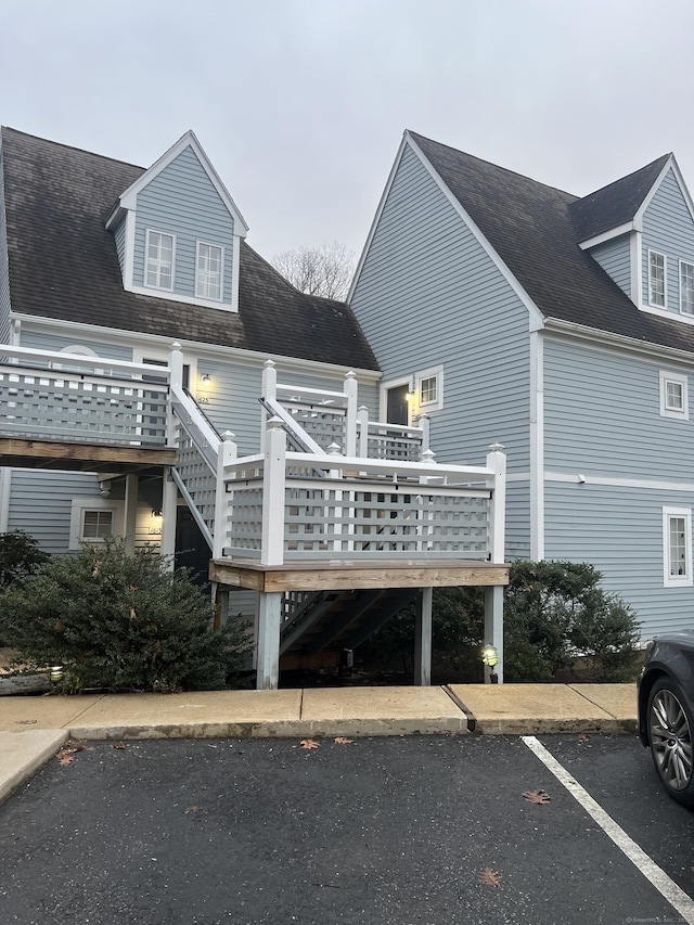 back of house with uncovered parking, stairs, and a deck