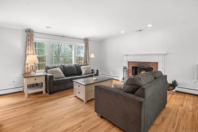 living area featuring a fireplace, light wood-style floors, visible vents, and a baseboard radiator