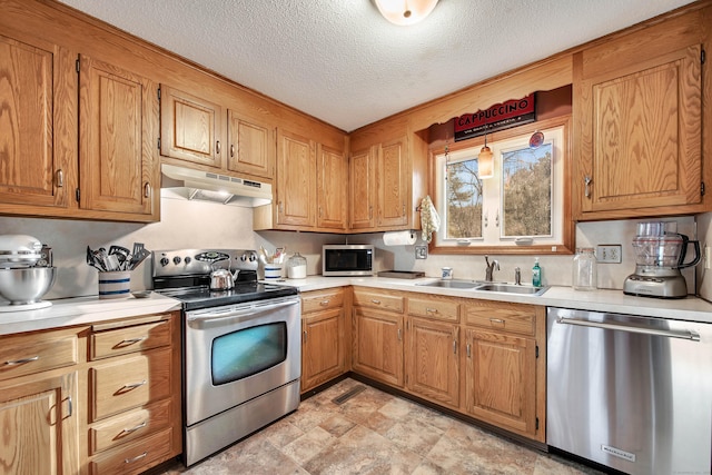 kitchen with a textured ceiling, under cabinet range hood, a sink, light countertops, and appliances with stainless steel finishes