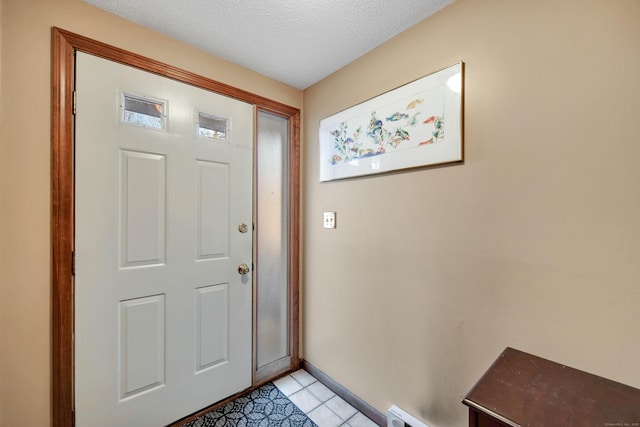 entryway with a textured ceiling, baseboards, and light tile patterned floors