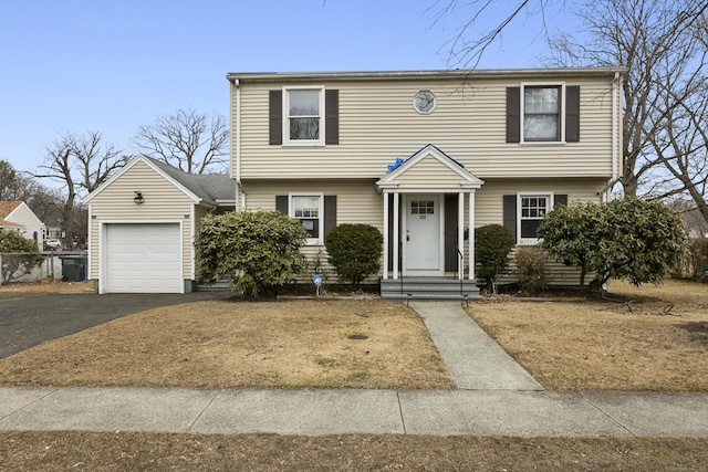 colonial-style house featuring a garage and aphalt driveway