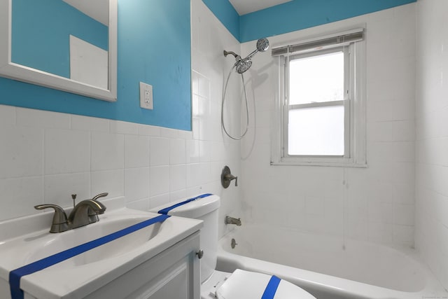 bathroom with tub / shower combination, tile walls, toilet, and vanity