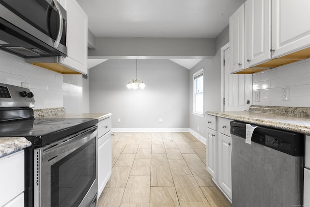 kitchen featuring lofted ceiling, white cabinetry, baseboards, appliances with stainless steel finishes, and an inviting chandelier